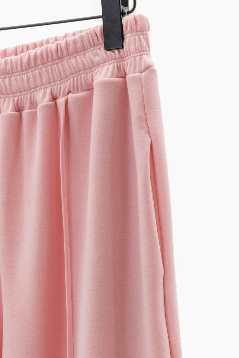 Pink pants on a hanger against a white background