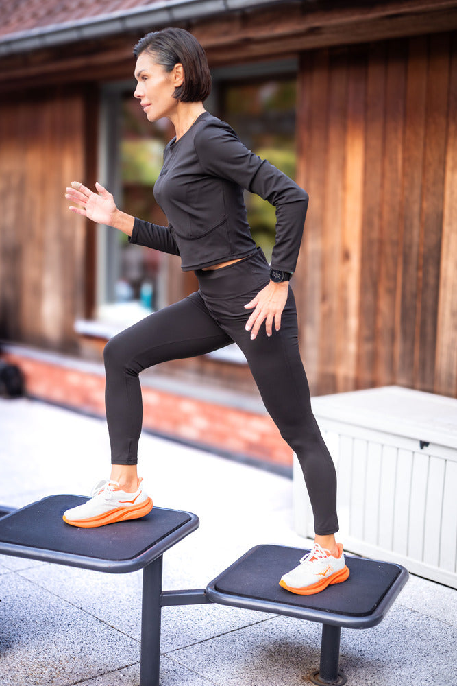 Woman exercising on a step machine outdoors.