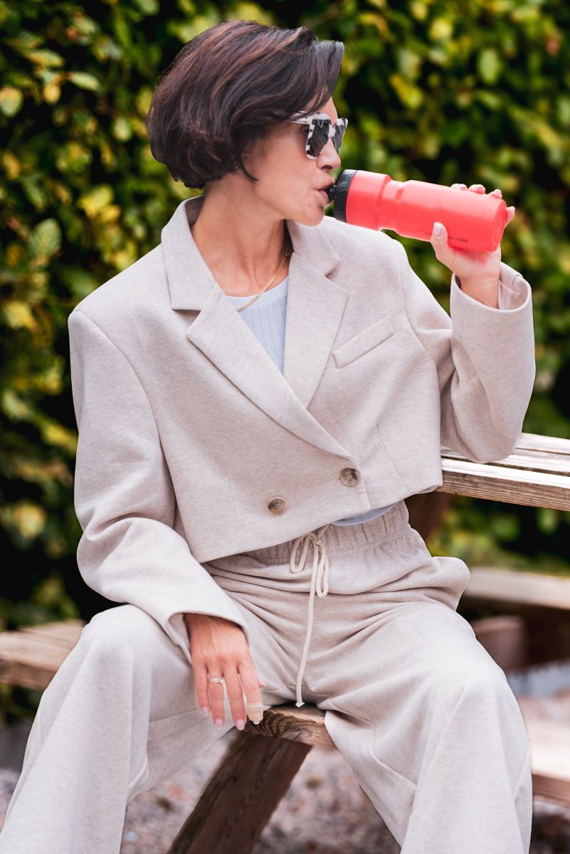 Person in light-colored outfit drinking from a red cup outdoors
