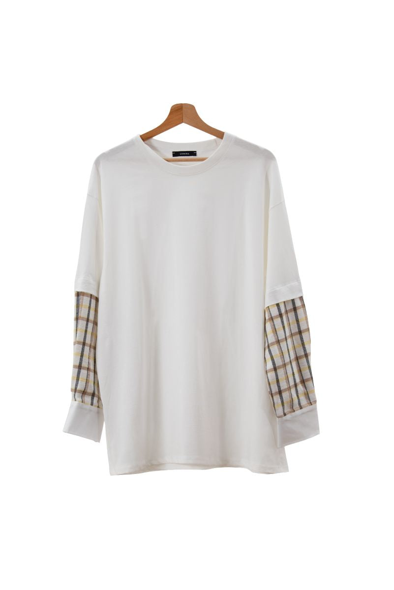 White sweater with plaid sleeves on a wooden hanger against a white background